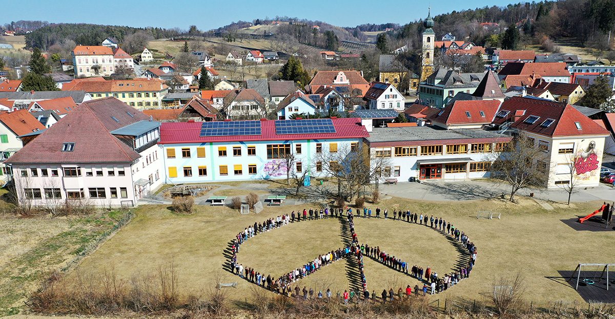 Volksschule Markt Hartmannsdorf - Schülerinnen und Schüler bilden ein Peace-Zeichen am Schulhof